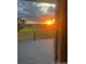 View from sliding glass door onto back deck area with sunset over distant green field with fence at 46531 Sundance Trl, Parker, CO 80138