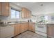 Well-lit kitchen featuring wooden cabinets, a window, and white appliances, providing a functional and appealing cooking space at 46531 Sundance Trl, Parker, CO 80138