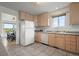 Bright kitchen with wood cabinets, tile floor, white appliances, and a view into the dining area, creating an inviting space at 46531 Sundance Trl, Parker, CO 80138