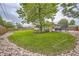 Lush backyard featuring a well-maintained lawn, mature trees, a trampoline, and rock landscaping at 6046 Vrain St, Arvada, CO 80003