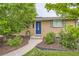 Close-up of the brick home's entrance with a blue door, trimmed shrubs, and manicured lawn at 6046 Vrain St, Arvada, CO 80003