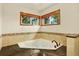 Bathroom showcasing a corner soaking tub with decorative tile surround and two windows at 7895 W 67Th Ave, Arvada, CO 80004