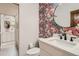 Stylish powder room features a round mirror, white vanity, and vibrant patterned wallpaper at 6102 S Aberdeen St, Littleton, CO 80120