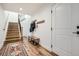 Inviting hallway featuring wooden floors, a staircase, and a bench with coat hooks by the door at 6102 S Aberdeen St, Littleton, CO 80120