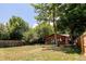 Spacious backyard featuring lawn, mature trees, and a charming wooden house with blue French doors at 1878 S Gilpin St, Denver, CO 80210