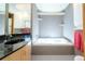 A large tub with tiled walls, nice cabinet and a shiny black counter top at 1878 S Gilpin St, Denver, CO 80210