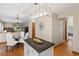 View of kitchen island with black granite countertops, white cabinets, and dining area at 20922 E Crestline Cir, Centennial, CO 80015