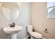 Modern half bathroom featuring a pedestal sink, oval mirror, and toilet with a view from the window at 1715 Pioneer Cir, Lafayette, CO 80026
