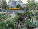 Landscaped backyard showcasing flowers, a stone bench, and a view of the blue house at 1715 Pioneer Cir, Lafayette, CO 80026