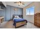 Comfortable bedroom with a wood bed frame, modern ceiling fan, a blue accent wall and ample natural light from the windows at 4811 River Highlands Loop, Elizabeth, CO 80107