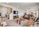 Open-concept living room with carpet, neutral tones, and seamless flow to the kitchen and dining areas at 4811 River Highlands Loop, Elizabeth, CO 80107