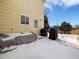 Backyard area featuring a covered outdoor furniture and barbeque grill space, with winter snow cover at 13577 Quivas St, Denver, CO 80234