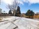 Spacious backyard with a wood fence, fire pit, and snow-covered ground and concrete patio at 13577 Quivas St, Denver, CO 80234