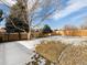 Spacious backyard with partial snow cover, a fence and small garden areas at 13577 Quivas St, Denver, CO 80234