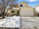 Charming home featuring a two-car garage and snow covered front yard at 13577 Quivas St, Denver, CO 80234
