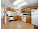 Well-equipped kitchen with white appliances, wood cabinets, and efficient layout for cooking at 13577 Quivas St, Denver, CO 80234