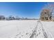 Wide backyard with fresh snow and a sidewalk leading to the townhomes with a beautiful blue sky at 2761 S Xanadu Way, Aurora, CO 80014