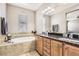 The bathroom has a double sink vanity with a tub surrounded by tile with a window at 3370 Cascina Cir # D, Highlands Ranch, CO 80126