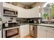 Fully equipped kitchen with stainless steel appliances, mosaic backsplash, and white cabinets at 8422 S Upham Way # H75, Littleton, CO 80128