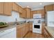 Efficient kitchen with light wood cabinets, white appliances, and granite countertops, offering a practical cooking space at 8487 Everett Way # E, Arvada, CO 80005