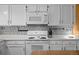 Close-up view of the kitchen area featuring white appliances, tile backsplash, and granite countertops at 17613 E Ohio Cir, Aurora, CO 80017
