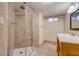 Bathroom with tiled shower, wood vanity, and window at 6095 W 47Th Ave, Wheat Ridge, CO 80033