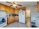 Cozy kitchen with wood cabinets, white appliances and neutral tile floors with a connecting hallway at 6095 W 47Th Ave, Wheat Ridge, CO 80033