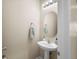 Simple half-bathroom features a white pedestal sink, a round mirror, and neutral-colored walls at 5591 Canyon View Dr, Castle Rock, CO 80104