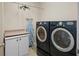 Modern laundry room with front-loading washer and dryer, white cabinets, and an ironing board at 5591 Canyon View Dr, Castle Rock, CO 80104
