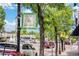 Street view in Highland Square, with shops, traffic, and local ambiance captured amidst lush green trees at 3019 Meade St, Denver, CO 80211