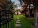Home's backyard with black metal gate, lush green grass, stone pathway and string lights at 3339 Lowell Blvd, Denver, CO 80211