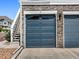 Attached garage with a blue door, stone facade, and convenient access via nearby exterior staircase at 5755 S Buchanan Ct # E, Aurora, CO 80016