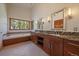 Bright bathroom featuring a soaking tub, granite counters, wood cabinetry, and forest views at 5197 Bear Mountain Dr, Evergreen, CO 80439