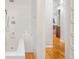 Bright white bathroom with a soaking tub, tiled wall, shower head, and wood floors at 2228 N Race St, Denver, CO 80205