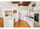 Modern white kitchen features exposed beams, stainless appliances, white cabinets, hardwood floors, and a window at 2228 N Race St, Denver, CO 80205