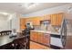 This is an open kitchen featuring wooden cabinets, tile backsplash, black appliances, and dining table at 7160 S Wenatchee Way # F, Aurora, CO 80016