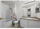 A bathroom features a tub with floral shower curtain and vanity with updated light fixture at 12816 Ironstone Way # 203, Parker, CO 80134