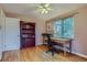 Cozy bedroom featuring hardwood floors, a ceiling fan, a bookcase, and a large window at 6260 W 45Th Pl, Wheat Ridge, CO 80033