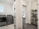 Laundry room with modern washer and dryer, open shelving, and doorway to bedroom at 875 Coal Bank Trl, Castle Rock, CO 80104