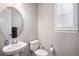Stylish half-bathroom featuring a pedestal sink, round mirror, and a toilet at 9380 Bear River St, Littleton, CO 80125