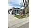 Charming home featuring a stylish front porch, vibrant blue door, and mature trees on a sunny day at 8885 W 64Th Pl, Arvada, CO 80004