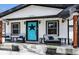 Charming home featuring a stylish front porch with cozy seating and a vibrant blue door at 8885 W 64Th Pl, Arvada, CO 80004