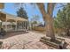 Spacious backyard with brick pavers, a covered patio area, a large tree, and a wooden fence at 4272 E 126Th Pl, Thornton, CO 80241