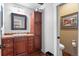 Bathroom with wood cabinets, a sink, a mirror and a toilet with a framed picture at 50 Albion St, Denver, CO 80220