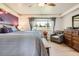 Sunlit main bedroom with large window, gray armchair, and wooden dresser at 2012 W 101St Ave, Thornton, CO 80260