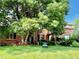 Charming red brick home with lush green lawn, mature trees, and 'For Sale' sign at 8461 Pawnee Ln, Niwot, CO 80503