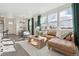 Bright and airy living room featuring a comfortable leather sofa, wood floors, and large windows at 9865 Biscay St, Commerce City, CO 80022