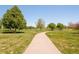 Scenic walking path winding through a lush green community space with mature trees at 19595 Mitchell Dr, Denver, CO 80249