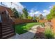Beautiful backyard featuring green grass, a wooden fence, stone pathway, and string lights at 119 Ward Ct, Lakewood, CO 80228