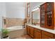 Bright bathroom with a bathtub with tile surround, wood cabinets and a single vanity at 119 Ward Ct, Lakewood, CO 80228